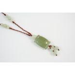 A CHINESE JADE PENDANT formed with a rounded rectangular-shaped section of jade, on silk mounted