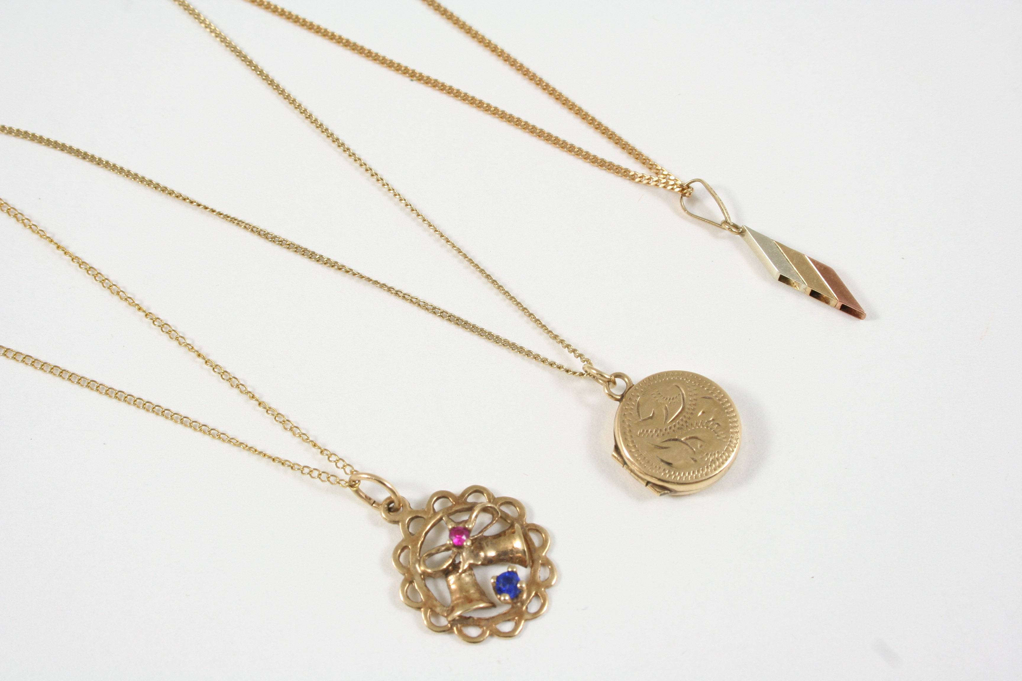 A 9CT. GOLD CIRCULAR LOCKET PENDANT with engraved decoration to the front case, together with two