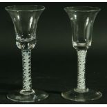 TWO 18TH CENTURY WINE GLASSES, with bell shaped bowls above white enamel double helix stems and