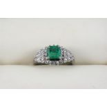 AN EMERALD AND DIAMOND CLUSTER RING the rectangular-shaped emerald is set within a surround of