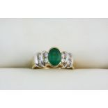 AN EMERALD AND DIAMOND RING the oval-shaped emerald is set with four circular-cut diamonds to each