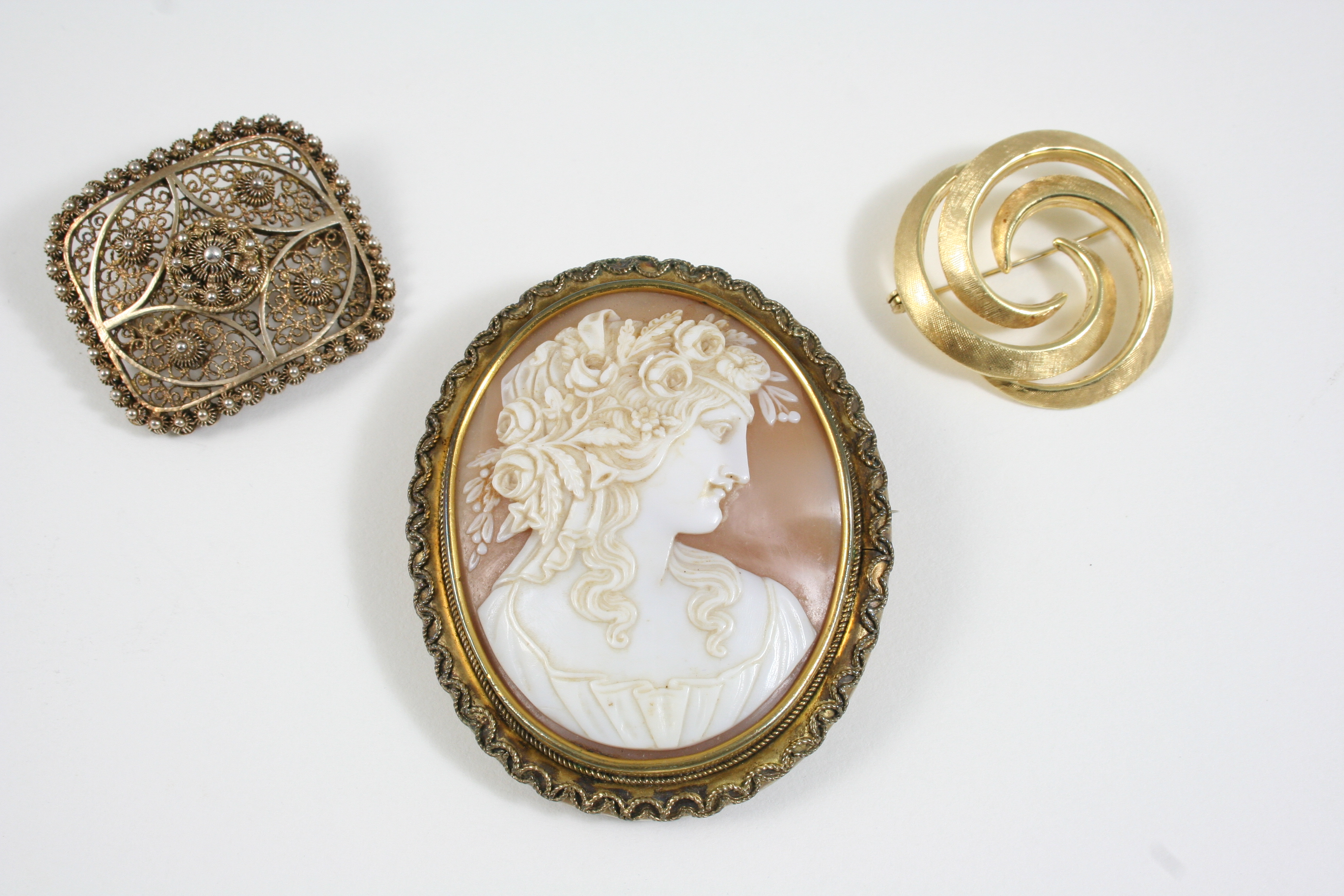 AN OVAL CARVED SHELL CAMEO BROOCH depicting a classical woman with flowers in her hair, in a gilt