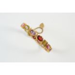 A SPINEL AND GOLD HALF HINGED BANGLE set with oval-shaped multi coloured spinels, in gold.