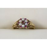 A VICTORIAN RUBY AND PEARL FLOWER HEAD RING set with small rubies and pearls in gold, with foliate