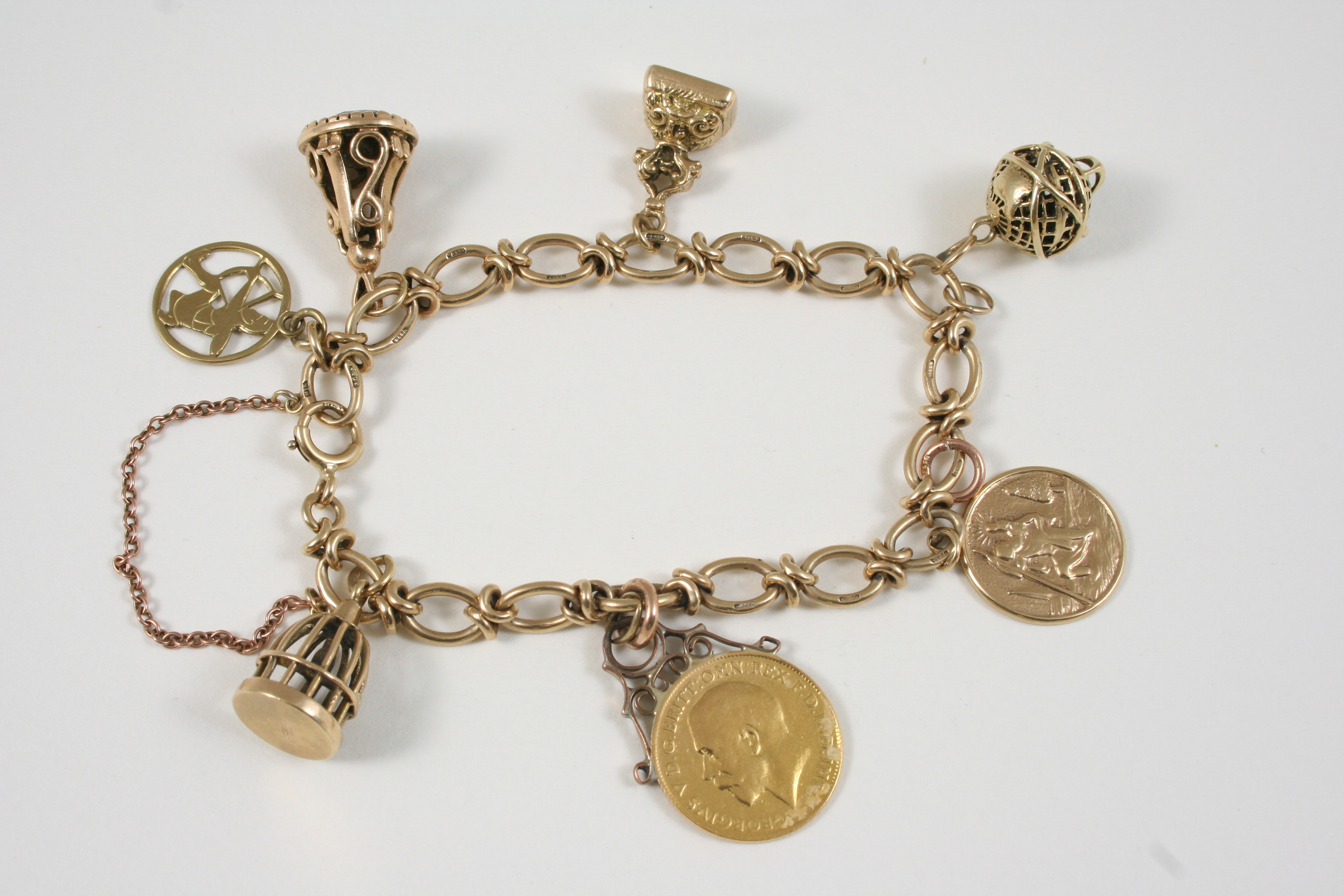 A 9CT. GOLD CHARM BRACELET set with assorted charms, 32 grams.