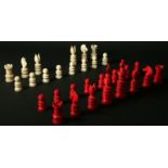 A RED AND WHITE IVORY PART CHESS SET each piece turned, the King 4ins. (10cms.) high