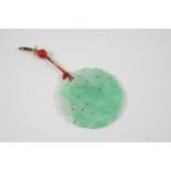 A CIRCULAR CARVED AND PIERCED JADE PENDANT with inscribed floral decoration, 5cm. dia.