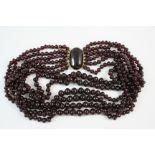 A SIX ROW GARNET BEAD NECKLACE the graduated garnet beads are set to an oval cabochon garnet and