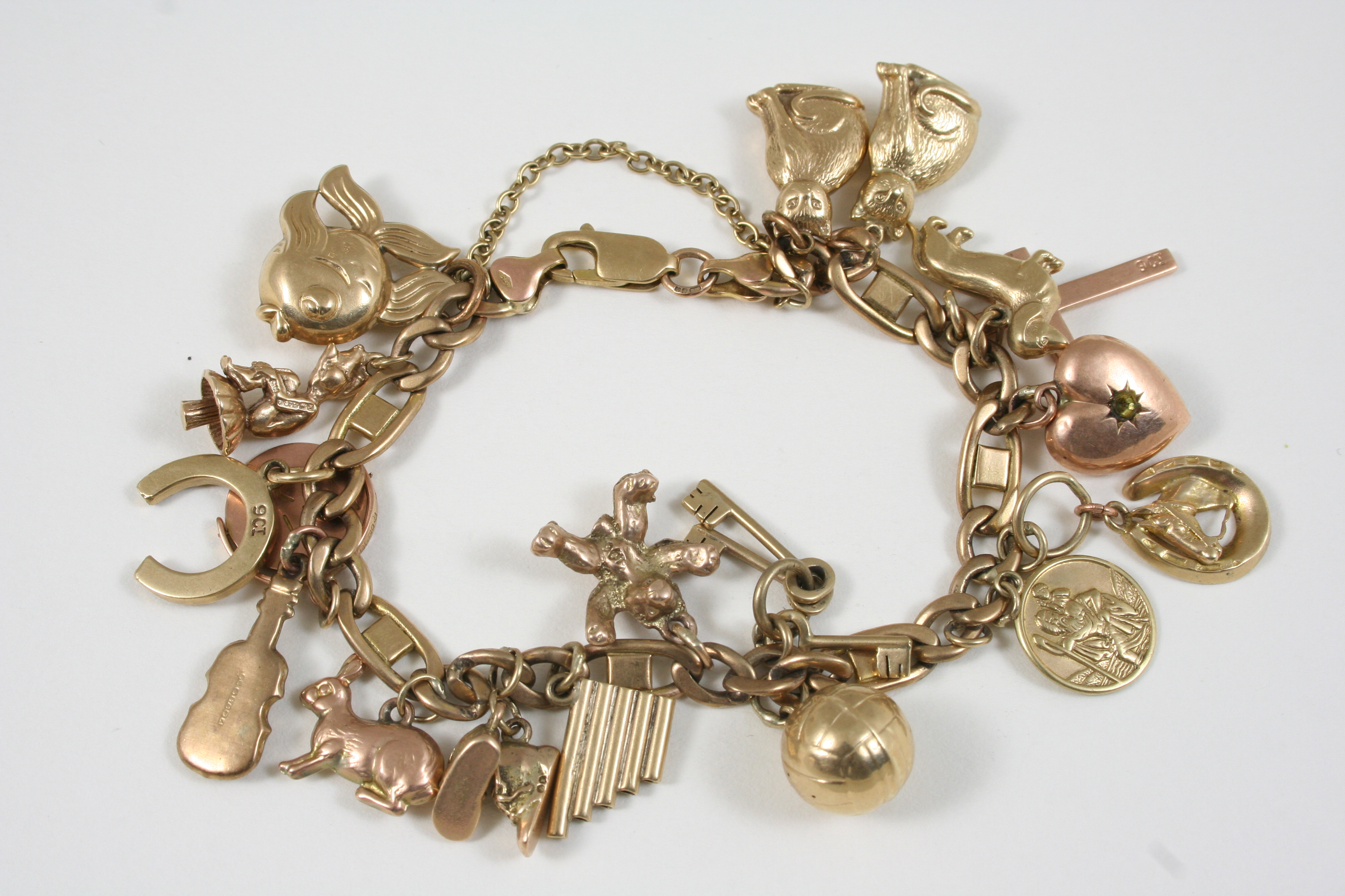 A 9CT. GOLD CHARM BRACELET set with assorted gold charms, 35 grams.