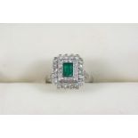 AN EMERALD AND DIAMOND CLUSTER RING the rectangular-shaped emerald is set within a double surround