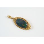 A BLACK OPAL AND GOLD BROOCH PENDANT the oval cabochon opal set within a gold floral mount, 4 x