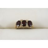 A GARNET THREE STONE RING the three oval-shaped garnets are set in gold. Size S.