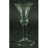 AN EIGHTEENTH CENTURY WINE GLASS, the wide bell shaped bowl above a plain stem, spreading foot