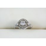 A DIAMOND CLUSTER RING the round brilliant-cut diamond weighs approximately 0.60 carats and is set