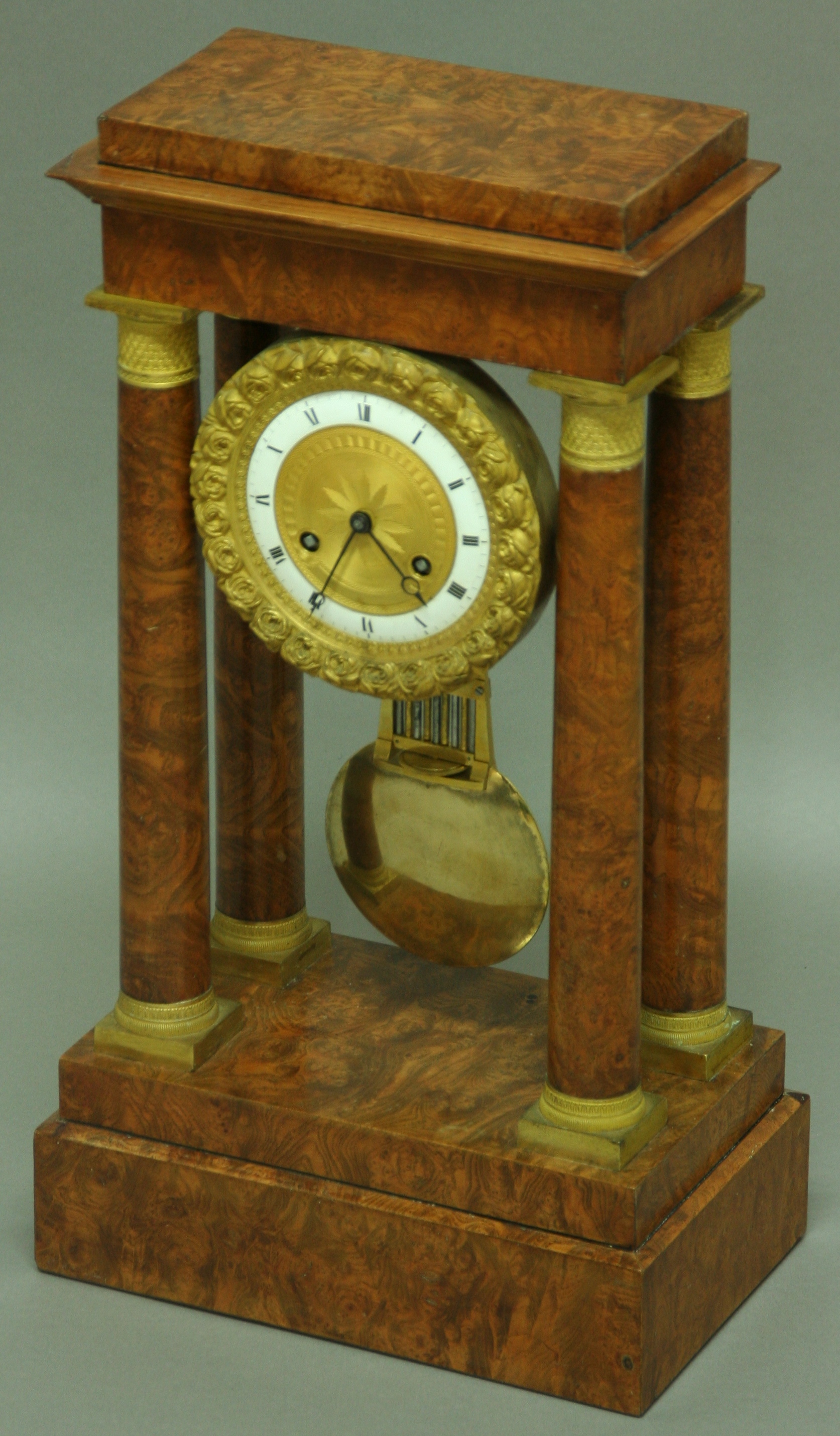 A FRENCH BURR WALNUT AND ORMOLU MOUNTED PORTICO CLOCK, the 4 1/2" enamelled chapter ring with engine