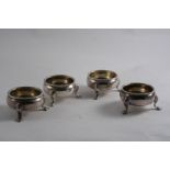 A SET OF FOUR GEORGE II SQUAT CIRCULAR SALTS on three feet, with corded rims, traces of a crest &