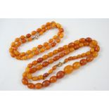 A SINGLE ROW GRADUATED AMBER BEAD NECKLACE formed with graduated oval-shaped beads, 28 grams,