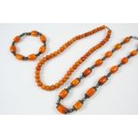 AN AMBER AND SILVER NECKLACE formed with slightly graduated amber beads, with ornate silver