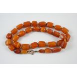 A SINGLE ROW AMBER BEAD NECKLACE formed with graduated irregular-shaped beads, 56cm. long, 44