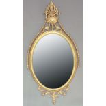 GEORGE III GILT GESSO MIRROR, circa 1800, the oval plate with acanthus crest, harebell swags,