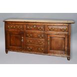GEORGE III OAK DRESSER BASE, the canted rectangular top above three fielded freize drawers and a run