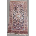 KASHAN RUG Central Iran, the indigo field of flowers around a madder cusped pole medallion framed by