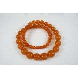A SINGLE ROW GRADUATED AMBER BEAD NECKLACE 62cm. long, 90.9 grams.