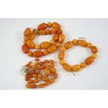 AN AMBER BEAD NECKLACE together with another amber bead necklace and a bracelet, total weight 81