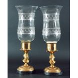 PAIR OF BRASS STORM LANTERNS, the waisted and engraved glass shades on bases with child bust