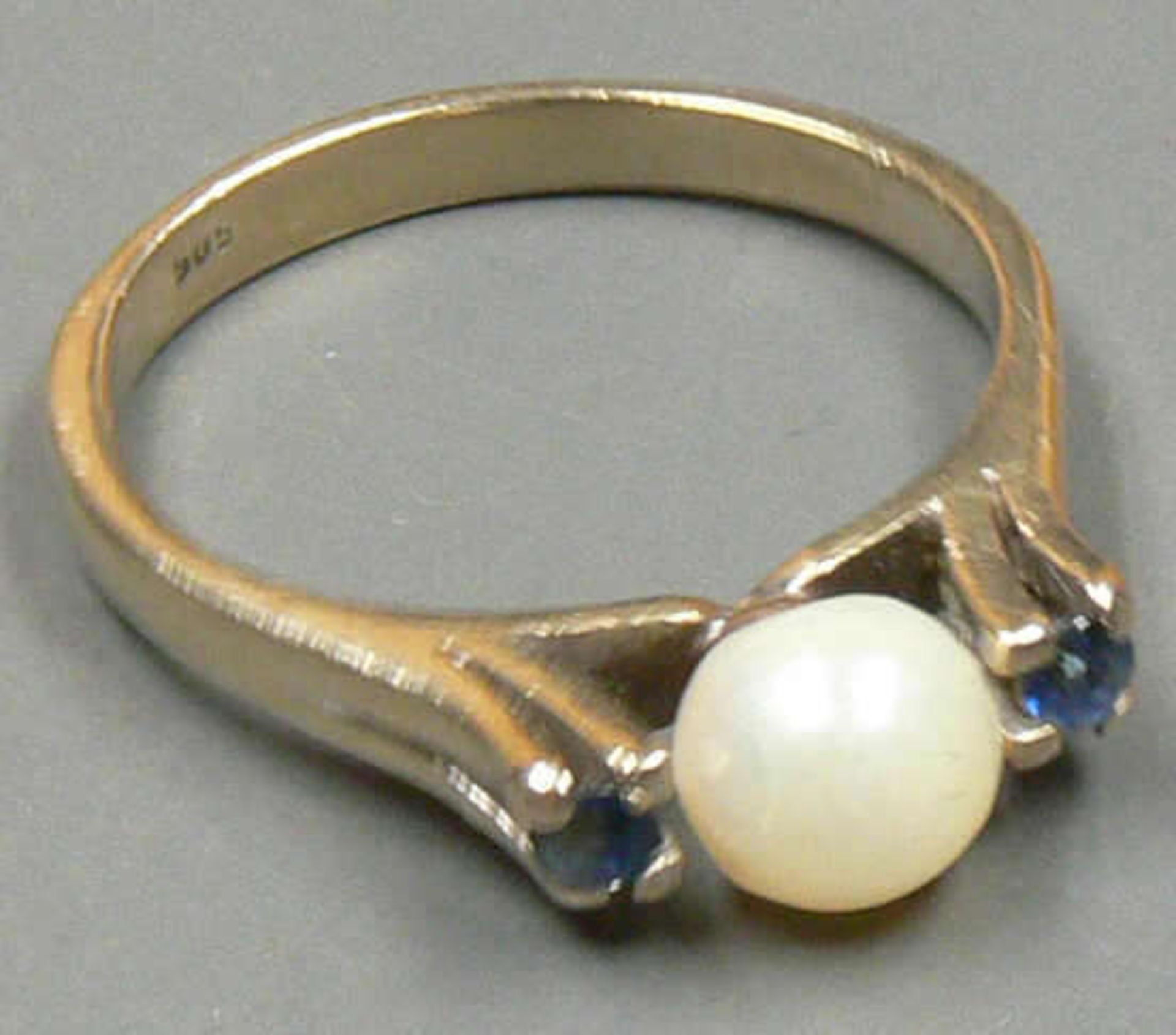 Damen Ring aus 585er Weißgold, besetzt mit 1 Perle flankiert von 2 Saphiren, Ringgröße: 55,5,