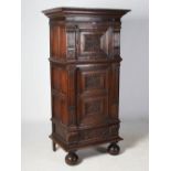 A 19th century oak tall cupboard, the moulded cornice above a single panelled cupboard door carved