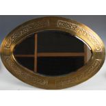 A Scottish Arts & Crafts brass wall mirror, the bevelled oval mirror plate enclosed within an