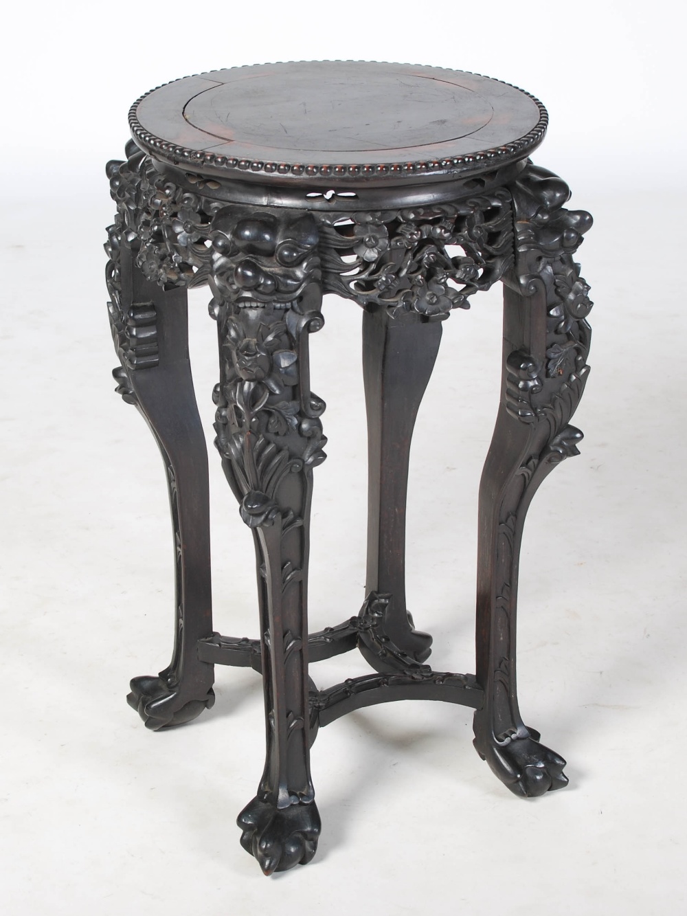 A Chinese dark wood jardiniere stand, Qing Dynasty, the circular panelled top above a pierced and