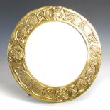 A Scottish Arts & Crafts brass wall mirror, the circular bevelled mirror plate within an embossed