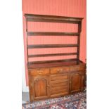 A George III oak dresser, the upright back with three open shelves and iron hanging hooks, above a