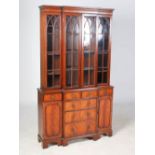 A reproduction mahogany breakfront bookcase in the George III style, the moulded cornice above