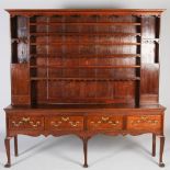 A George III oak dresser, the upright back with three open plate racks flanked by open recesses
