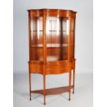 An Edwardian satinwood and marquetry inlaid serpentine display cabinet, the upper section with a