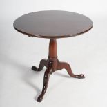 A George III mahogany snap top tripod table, the hinged circular top raised on a tapered cylindrical