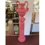 Large twin handled pink china urn on plinth