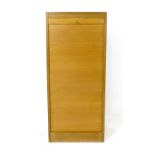 A 1960/70's beech tambour door cabinet, the interior with fitted shelves, on a plinth base, h. 114.