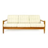 A 1970's teak framed three seater sofa with loose button upholstered cushions on circular straight