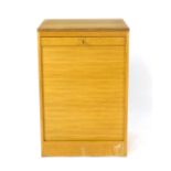 A 1970's oak tambour door cabinet, the interior with fitted shelves, on a plinth, h.