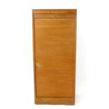 A 1960/70's teak tambour door cabinet, the interior with fitted shelves, on a plinth, h.