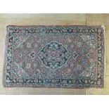 A hand woven Eastern rug, l. 120 cm, w. 74 cm CONDITION REPORT: Worn. Stained.