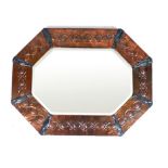 An Arts & crafts embossed copper mirror, the octagonal frame enclosing the bevelled glass mirror, h.