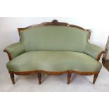 An early 20th century walnut and green fabric upholstered settee with carving to the cresting rail,