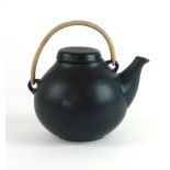 A 20th century black pottery teapot by Arabia of Finland with a wickerwork handle, h.