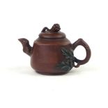 A Chinese teapot, the leaf and flower handle surmounting a buff squat body,