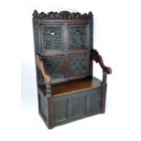 A Victorian 17th century-style oak settle with box seat and carved cresting rail over lift up seat